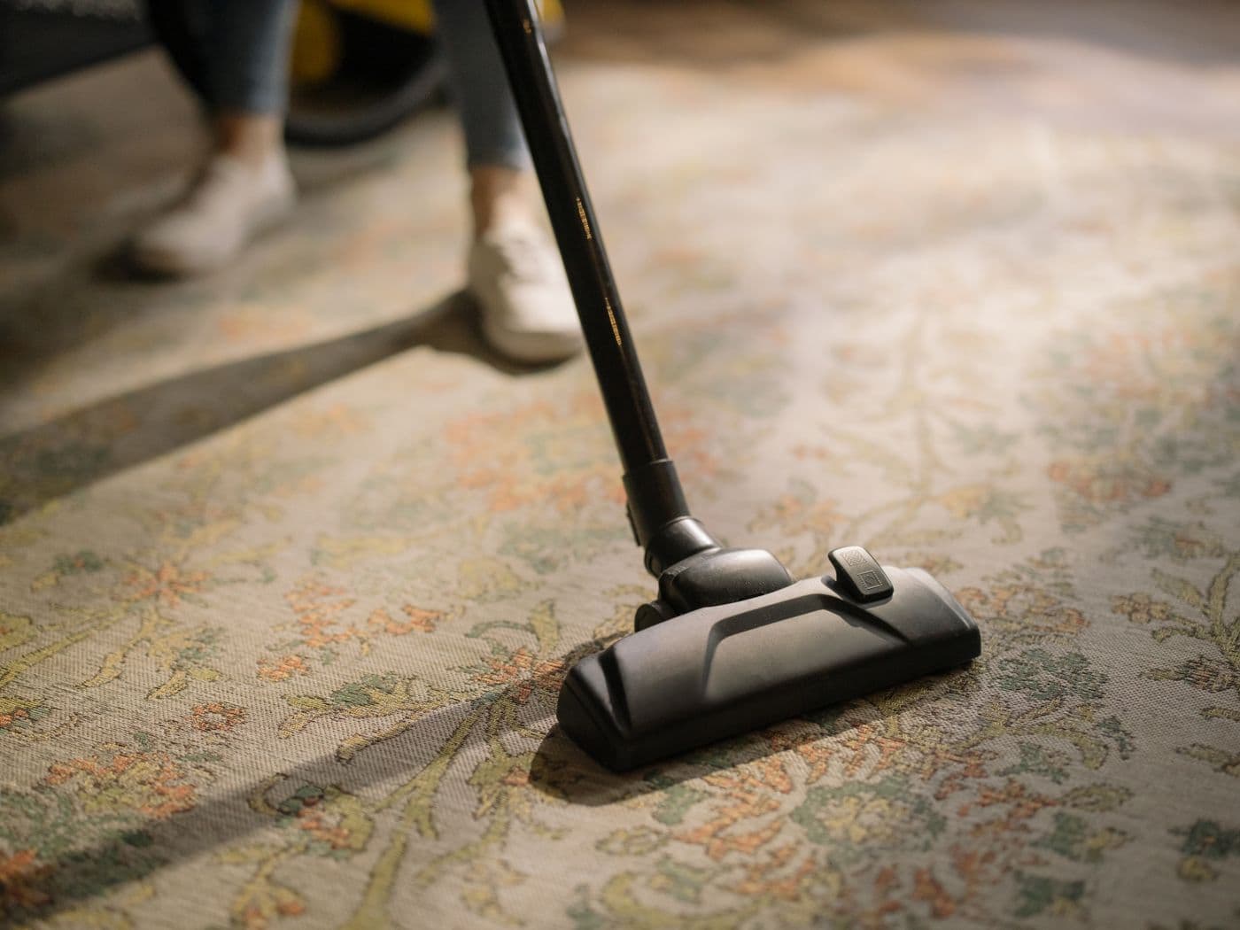 Vacuum cleaning an ornate area rug during professional carpet care