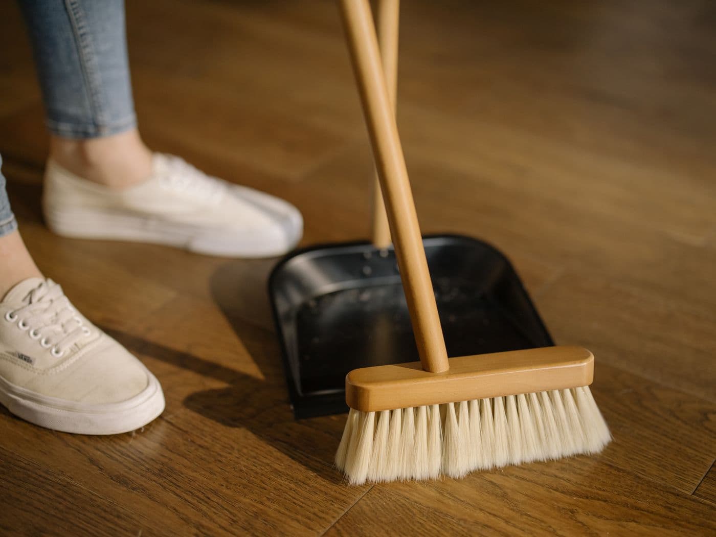 Broom and dustpan on hardwood floors during a regular home cleaning